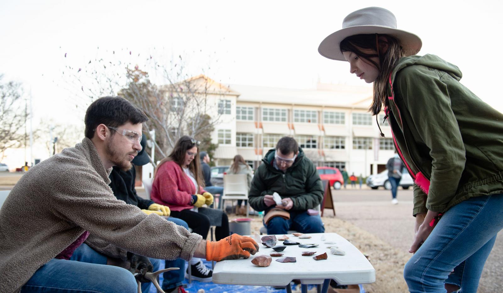 Three people make stone tools while another person watches